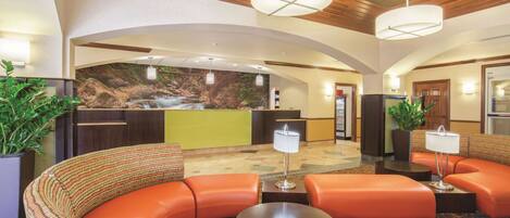 A lobby with a curved orange sofa, a reception desk, and a wall mural of a waterfall.