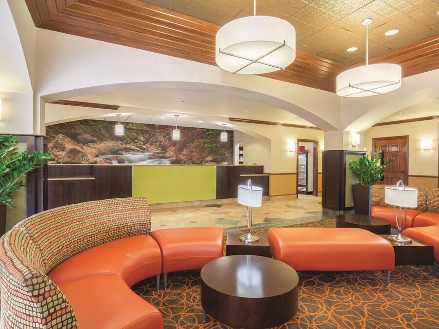 A lobby with a curved orange sofa, a reception desk, and a wall mural of a waterfall.