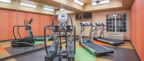Un gimnasio con cintas de correr, una bicicleta estática y una máquina de pesas.