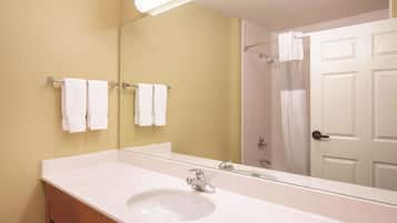 A bathroom with a white sink, a mirror, and two towels hanging on a rack.