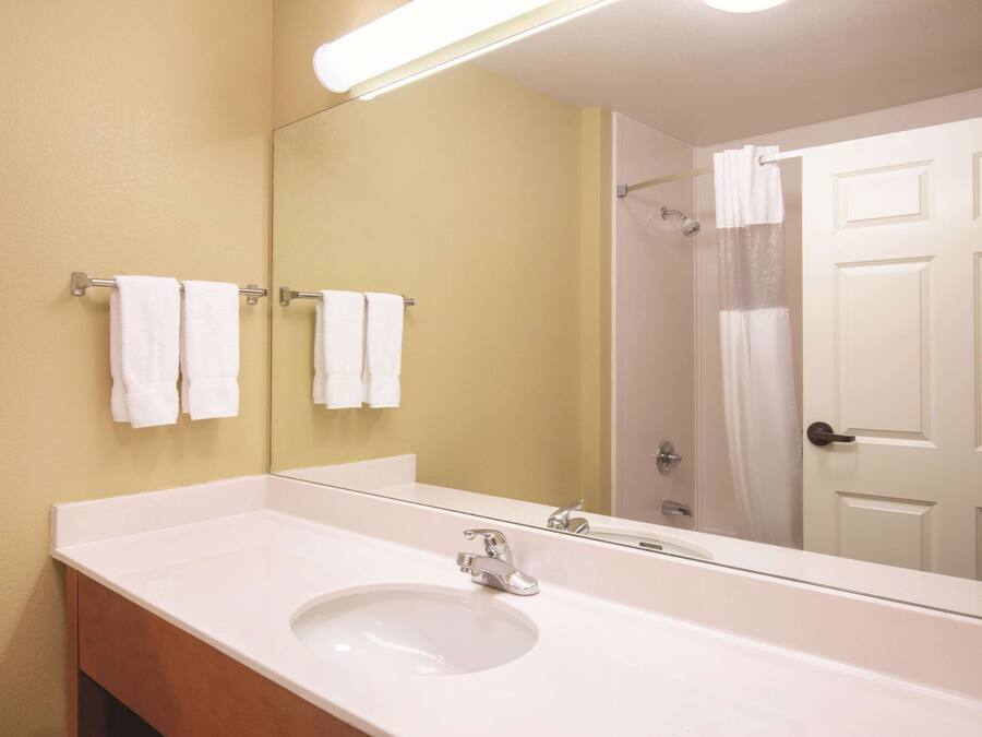 A bathroom with a white sink, a mirror, and two towels hanging on a rack.