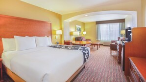 A hotel room with a large bed, a desk, a chair, a television, and a window with curtains. - La Quinta Inn & Suites by Wyndham Bentonville (Bentonville)