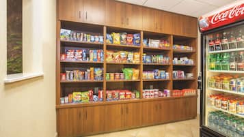 A snack and beverage display in a store with wooden shelves and a Coca-Cola refrigerator.