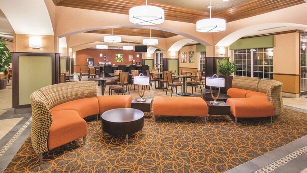 A lobby with a curved seating area, a reception desk, and a coffee station. - La Quinta Inn & Suites by Wyndham Bentonville (Bentonville)