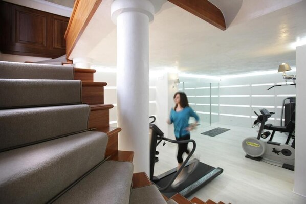 A modern home interior with a staircase, a treadmill, and exercise equipment.