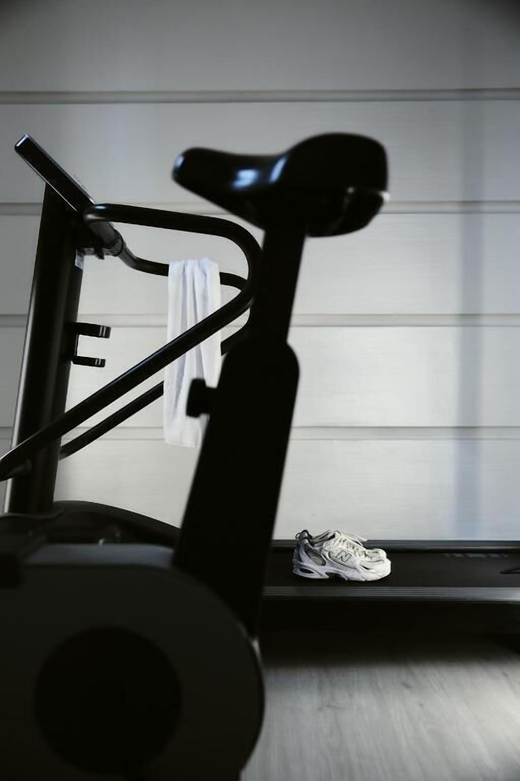 A stationary exercise bike with a pair of sneakers on the floor beside it.