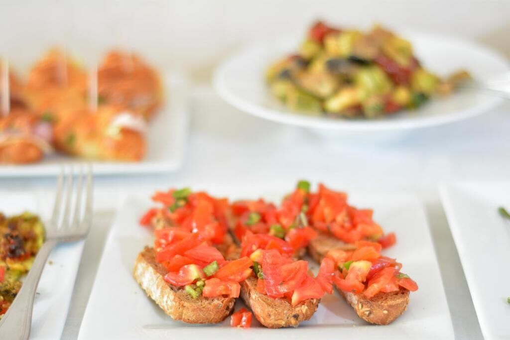 A plate of bruschetta with tomato and green toppings.