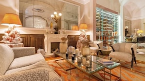 A spacious living room with a fireplace, comfortable seating, a glass coffee table, and a wine cellar. - Palazzo del Corso (Gallipoli)