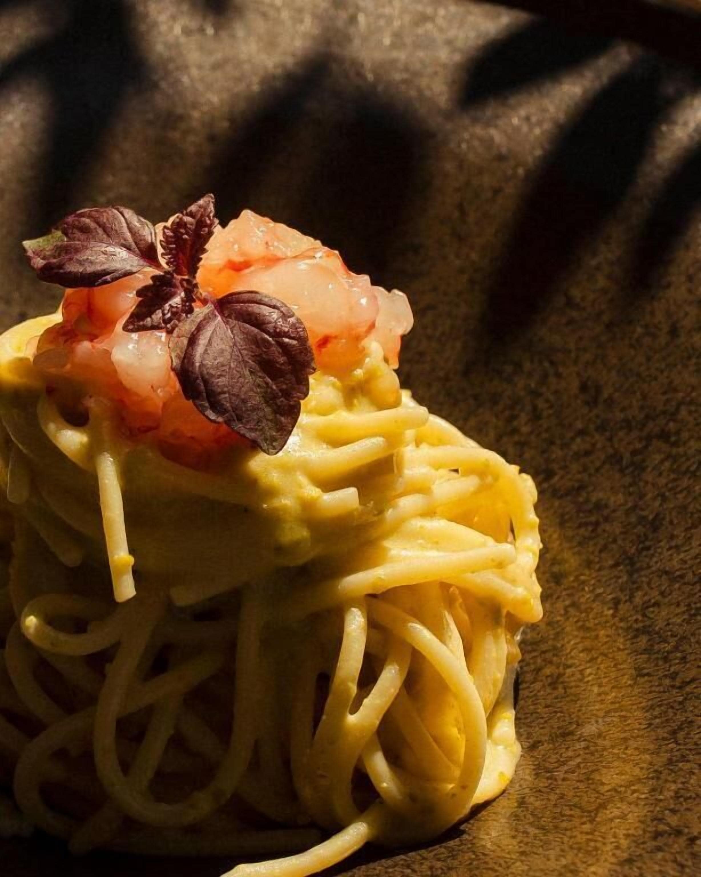 Primer plano de un plato de pasta con camarones y una guarnición.