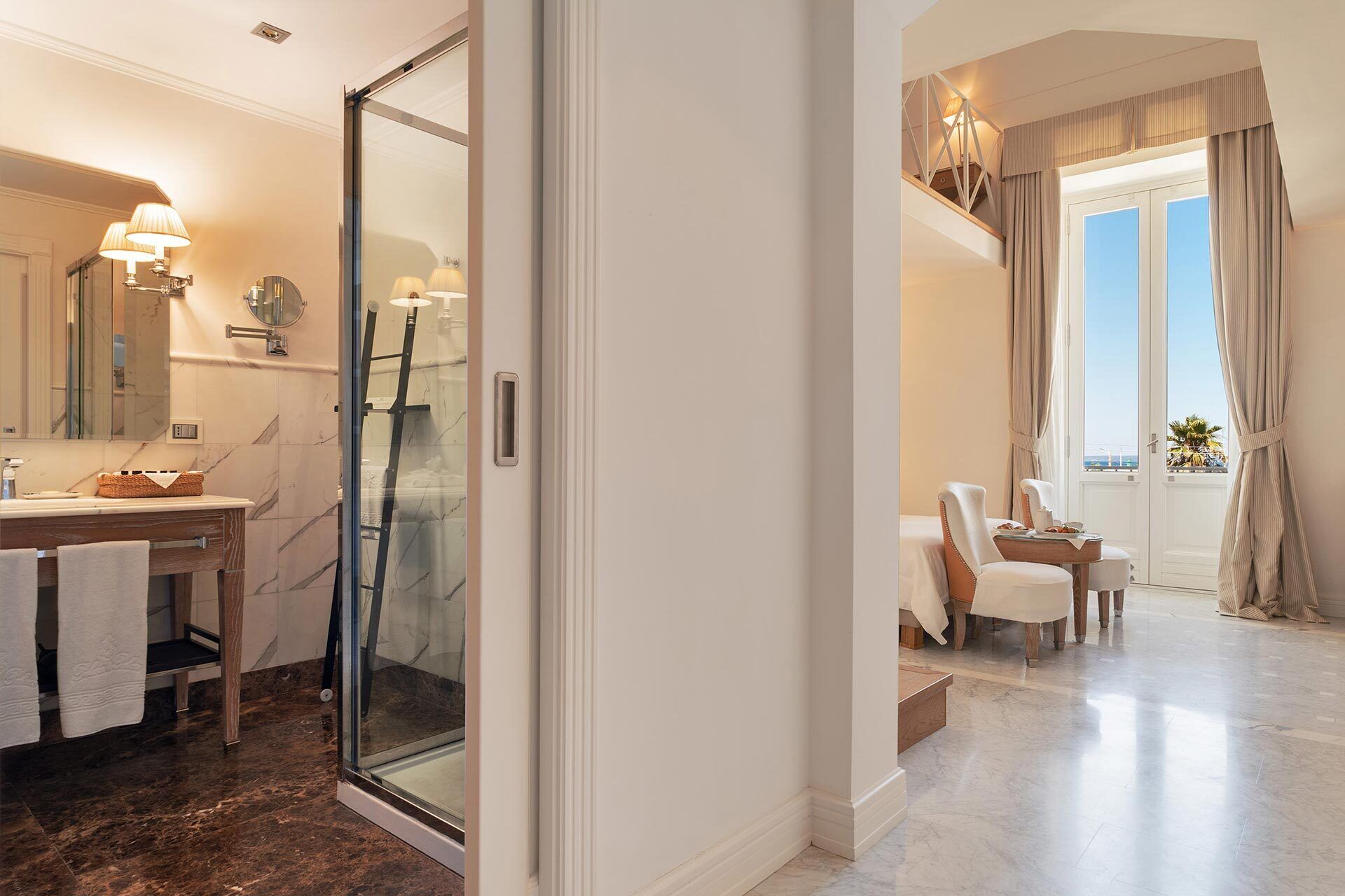 A modern bathroom with a glass shower, a vanity with a marble countertop, and a large mirror.