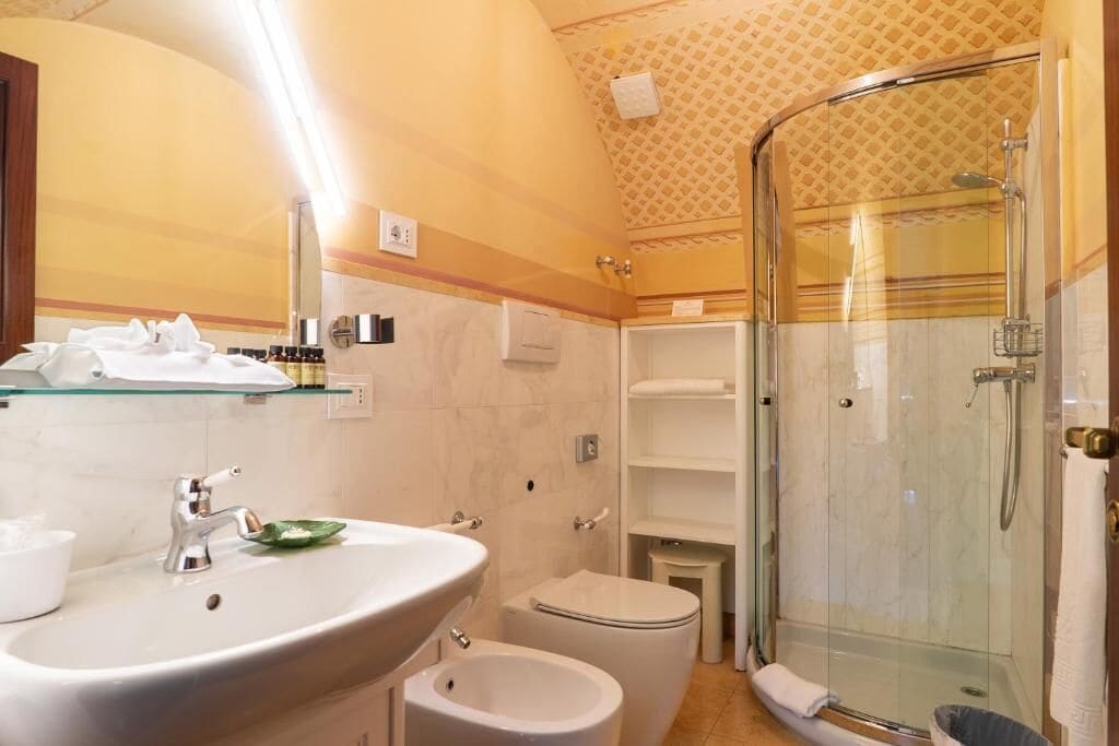 A bathroom with a sink, toilet, bidet, and glass-enclosed shower.