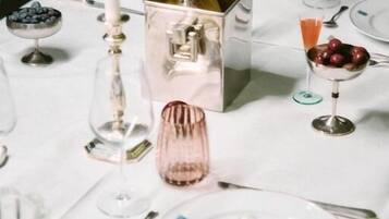 A table set for a meal with a bottle, a candle, and a bowl of fruit.