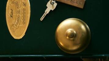 Una maleta verde con un candado de latón, una llave de latón y un llavero de latón que dice "SIMERALDO".