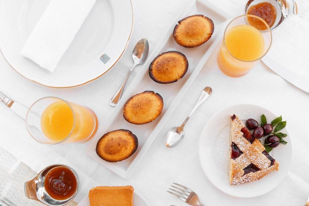 A breakfast setting with toast, jam, and a slice of pie on a white table.