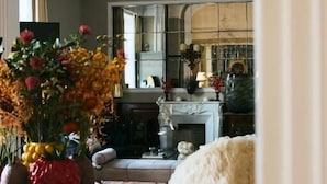 A cozy living room with a fireplace, a round table with a vase of flowers, and a fluffy chair. - Palazzo del Corso (Gallipoli)