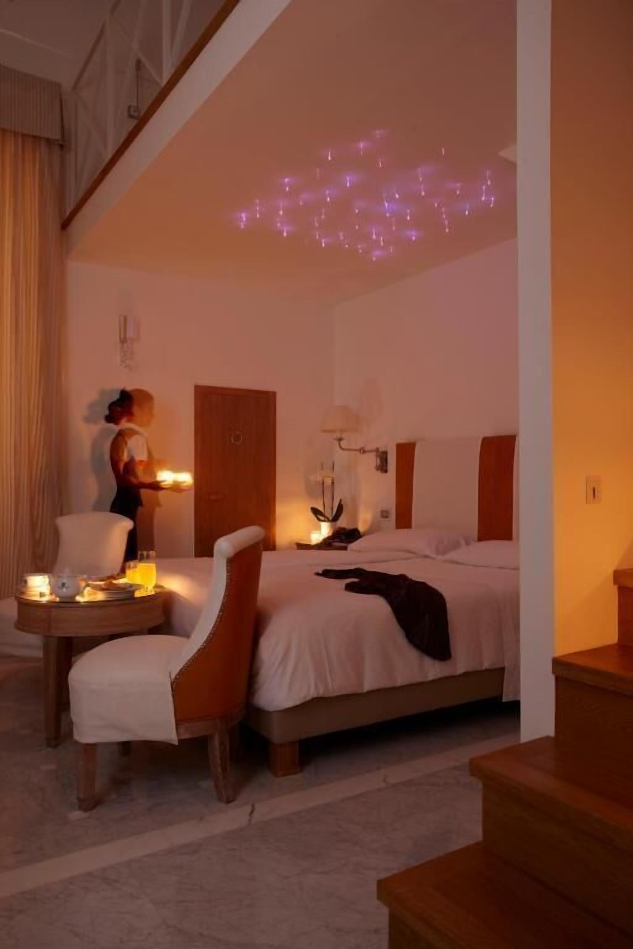 Ein Hotelzimmer mit Bett, Stuhl, Nachttisch und Deckenleuchte.