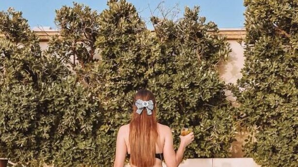 A person sitting by a pool with a clear view of the pool and a hedge in the background. - Palazzo del Corso (Gallipoli)