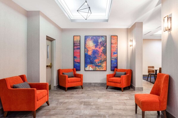 A spacious lobby with two orange armchairs, a large abstract painting, and a skylight. - Sleep Inn & Suites St Petersburg Gateway (St. Petersburg)