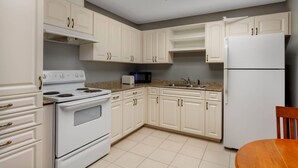 A kitchen with white cabinets, a stove, a microwave, and a refrigerator. - Sleep Inn & Suites St Petersburg Gateway (St. Petersburg)