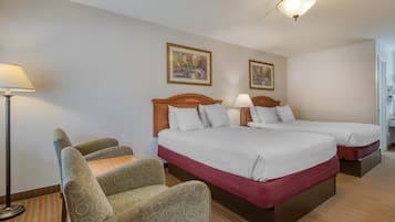 Ein Hotelzimmer mit zwei Betten, einem Schlafsofa, einer Lampe und zwei gerahmten Bildern an der Wand.