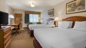 Habitación de hotel con dos camas, un escritorio, un televisor y una ventana con cortinas.