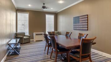 A conference room with a large wooden table, six chairs, and a flag on the wall.