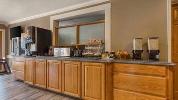 A kitchen with wooden cabinets, a coffee station, and a window with frosted glass.