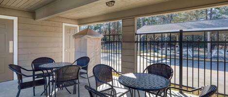 A covered patio with wicker furniture and a view of a parking lot.