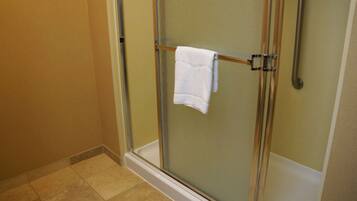 A glass-enclosed shower with a white towel hanging on a metal bar.