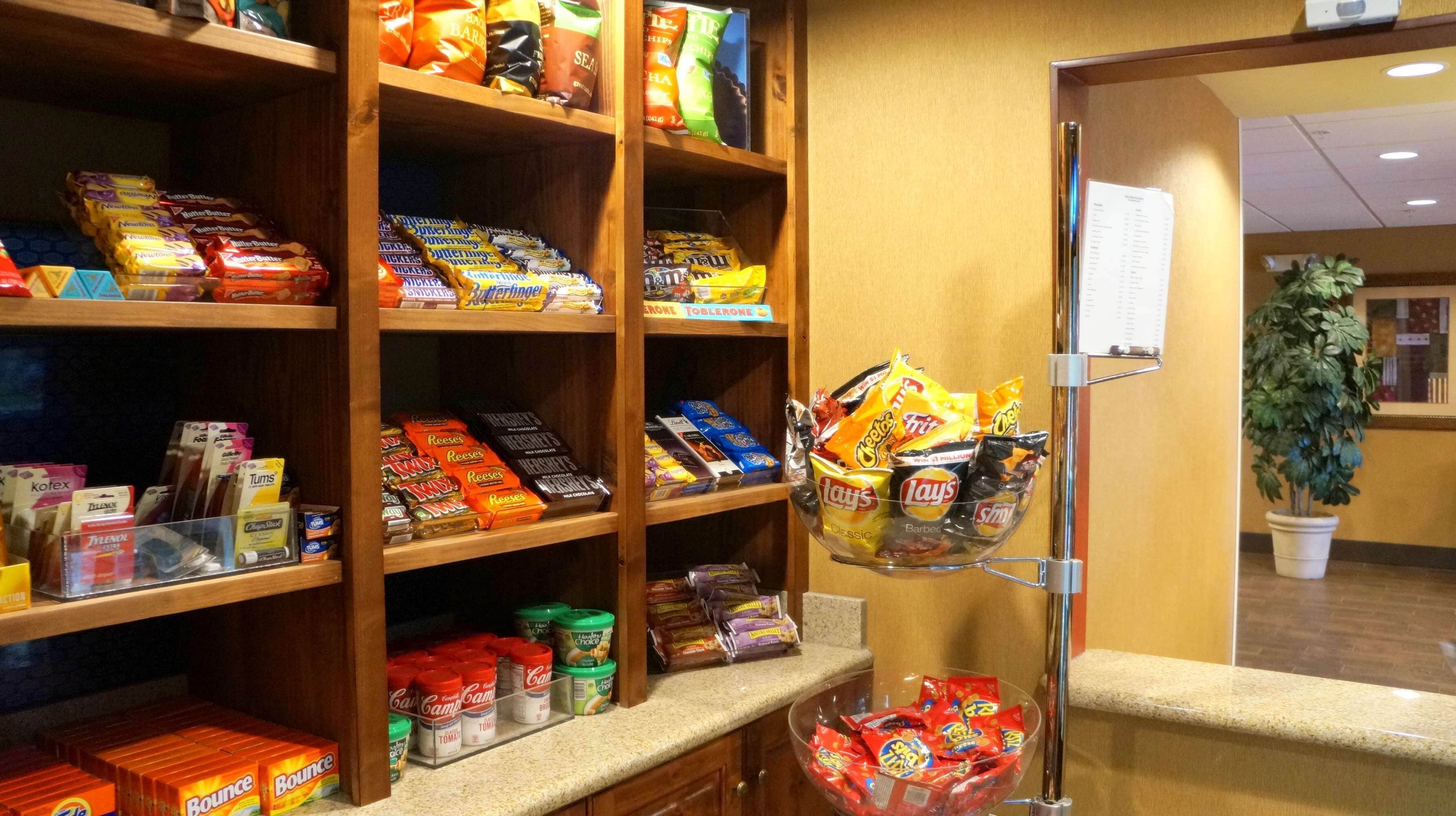 A snack display with various packaged foods and a small potted plant.
