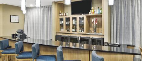 A bar area with a counter, bar stools, and a television mounted on the wall.