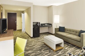 A hotel room with a kitchenette, a sofa, a TV, and a small table. - Holiday Inn Augusta West I-20 by IHG (Grovetown)