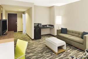 Una habitación de hotel con kitchenette, un sofá, un televisor y una pequeña mesa.