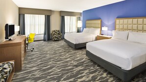A hotel room with two beds, a desk with a computer, a chair, and a large window with curtains. - Holiday Inn Augusta West I-20 by IHG (Grovetown)
