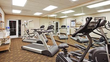 Un gimnasio con cintas de correr, elípticas y equipo de pesas.