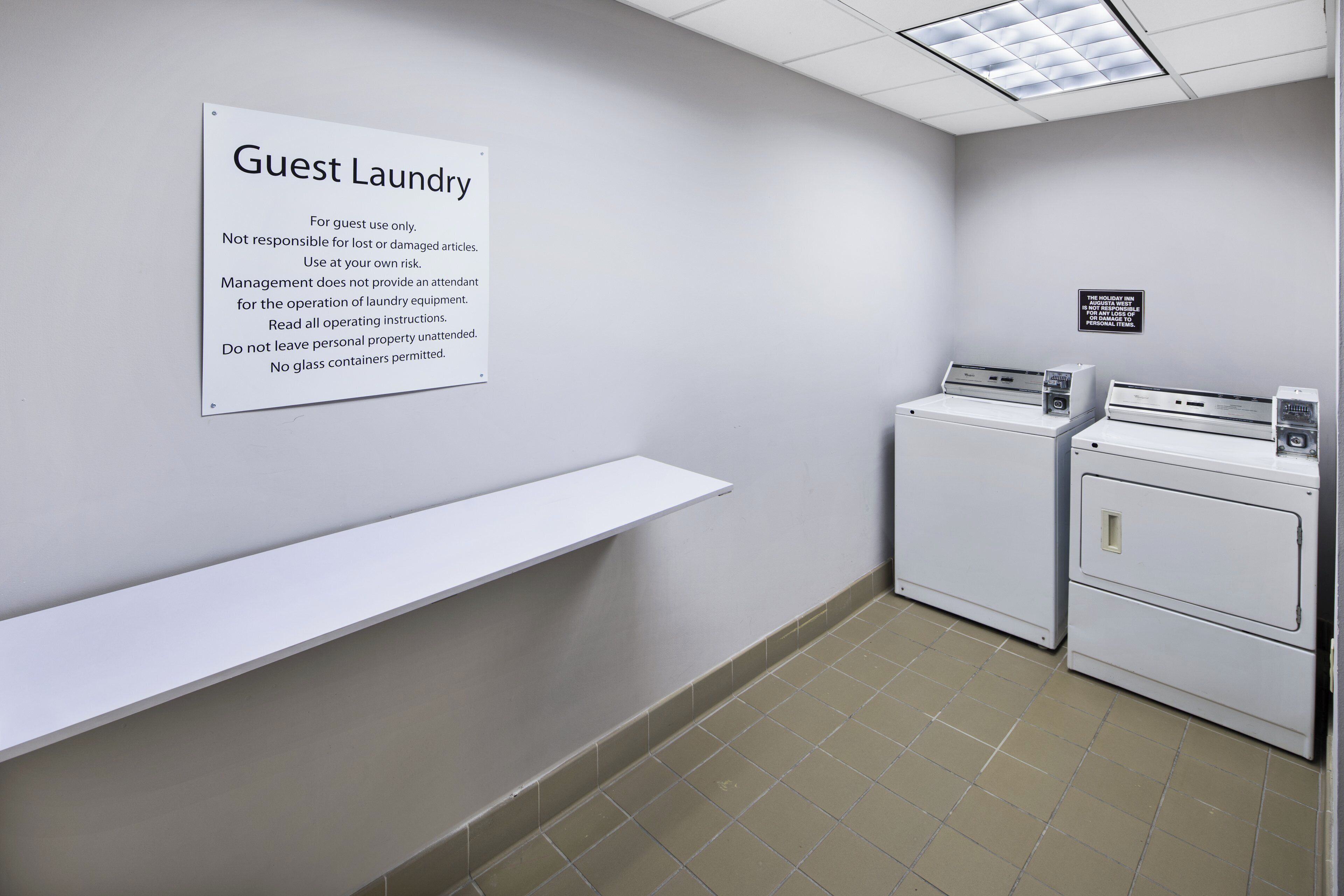 A guest laundry area with a sign detailing usage instructions and a notice about the Holiday Inn's location.