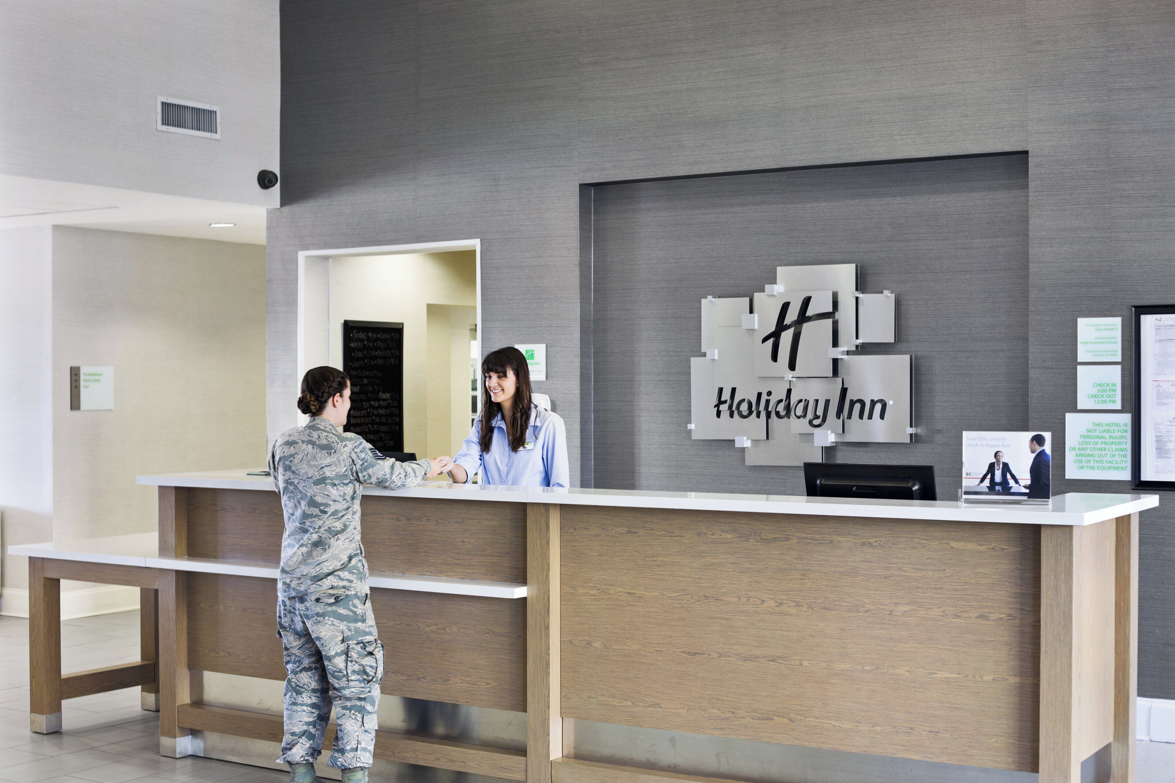 A Holiday Inn reception desk with a modern design, a check-in counter, and a digital display.