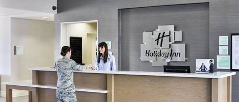 A Holiday Inn reception desk with a modern design, a check-in counter, and a digital display.