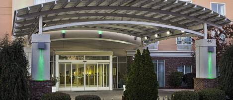 A hotel entrance with a covered walkway, glass doors, and a brick facade.