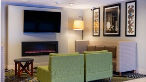 A lobby with a flat-screen TV, a fireplace, green patterned seating, and framed artwork on the walls. - Holiday Inn Express Hotel & Suites Salisbury - Delmar by IHG (Delmar)