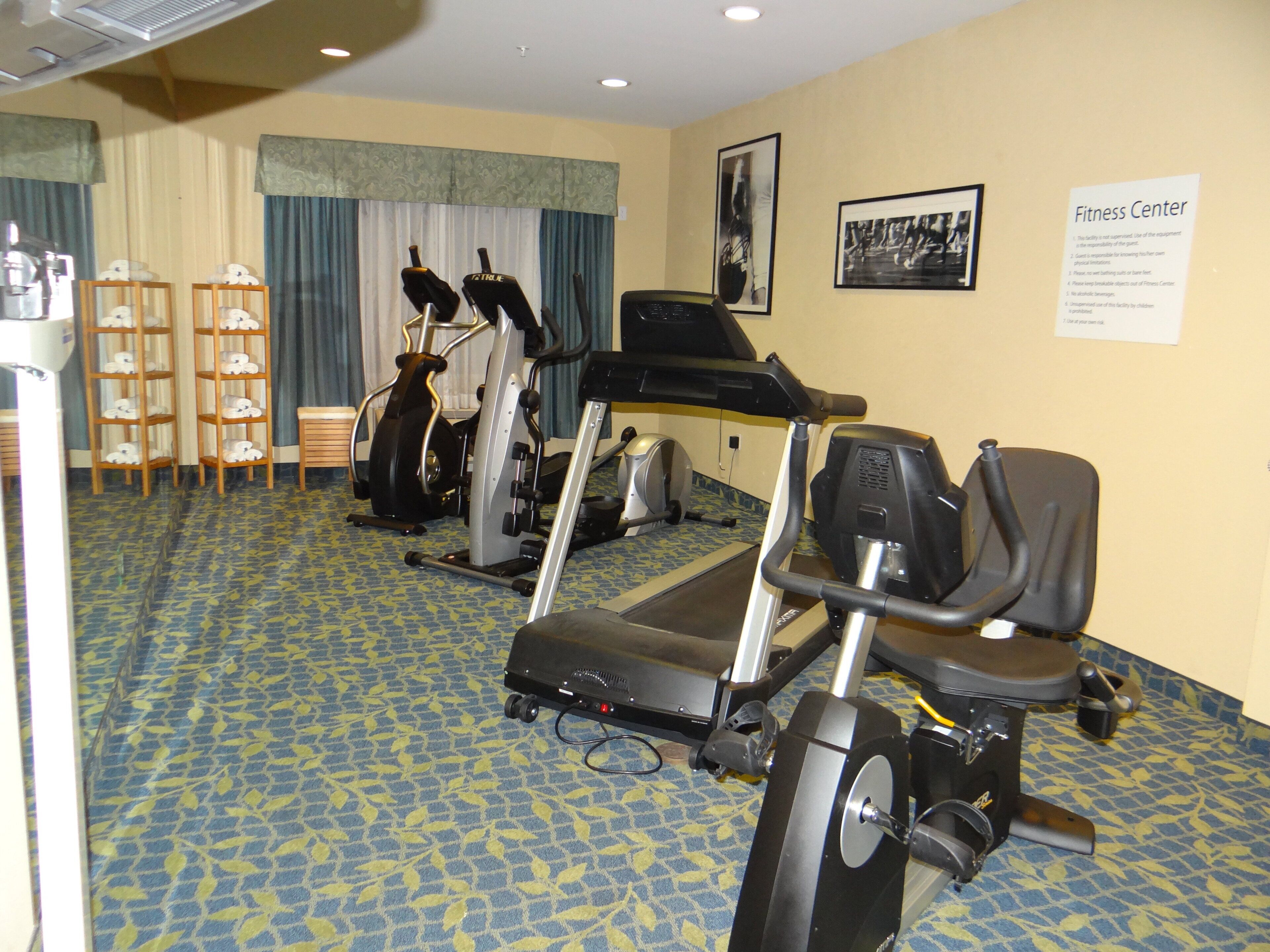 A fitness center with treadmills, stationary bikes, and a wall-mounted exercise machine.
