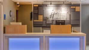 A reception desk with a Holiday Inn Express sign, a security camera, and a digital display. - Holiday Inn Express Hotel & Suites Salisbury - Delmar by IHG (Delmar)