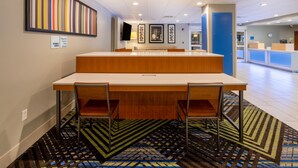 A hotel reception area with a reception desk, chairs, a patterned carpet, and a wall with a vertical art piece. - Holiday Inn Express Hotel & Suites Salisbury - Delmar by IHG (Delmar)