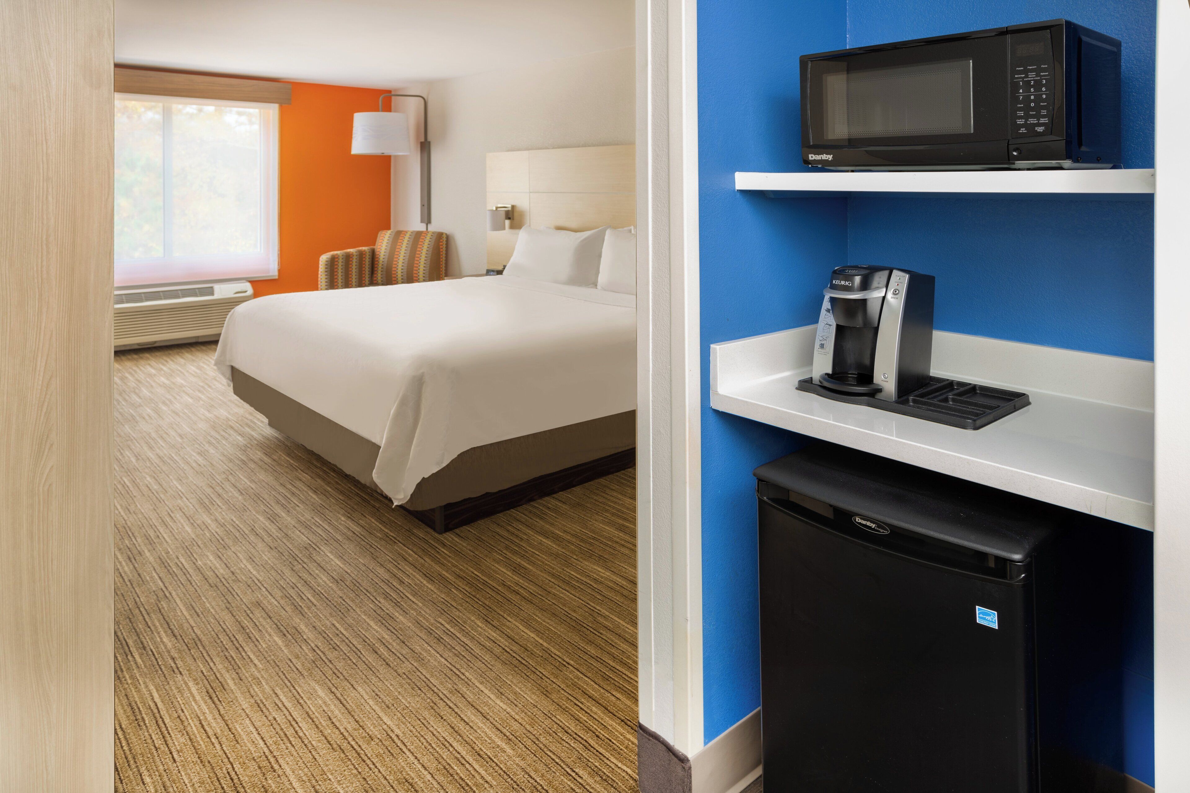 Une chambre d’hôtel équipée d’un lit, d’un four à micro-ondes, d’une machine à café et d’un mini-réfrigérateur.