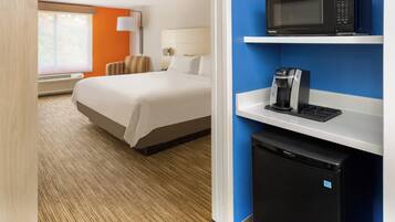 Une chambre d’hôtel équipée d’un lit, d’un four à micro-ondes, d’une machine à café et d’un mini-réfrigérateur.