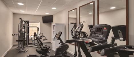 Un gimnasio con cintas de correr, elípticas y máquinas de pesas.