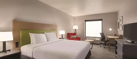 Una habitación de hotel con una cama grande, un escritorio, una silla, un televisor y una ventana.
