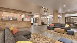 Un hall d’entrée spacieux avec un comptoir d’accueil, des canapés et une grande horloge au mur.