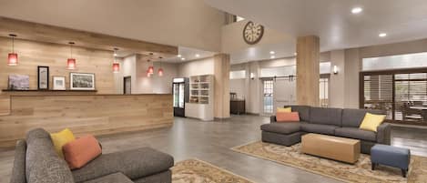 A spacious lobby with a reception desk, sofas, and a large clock on the wall.