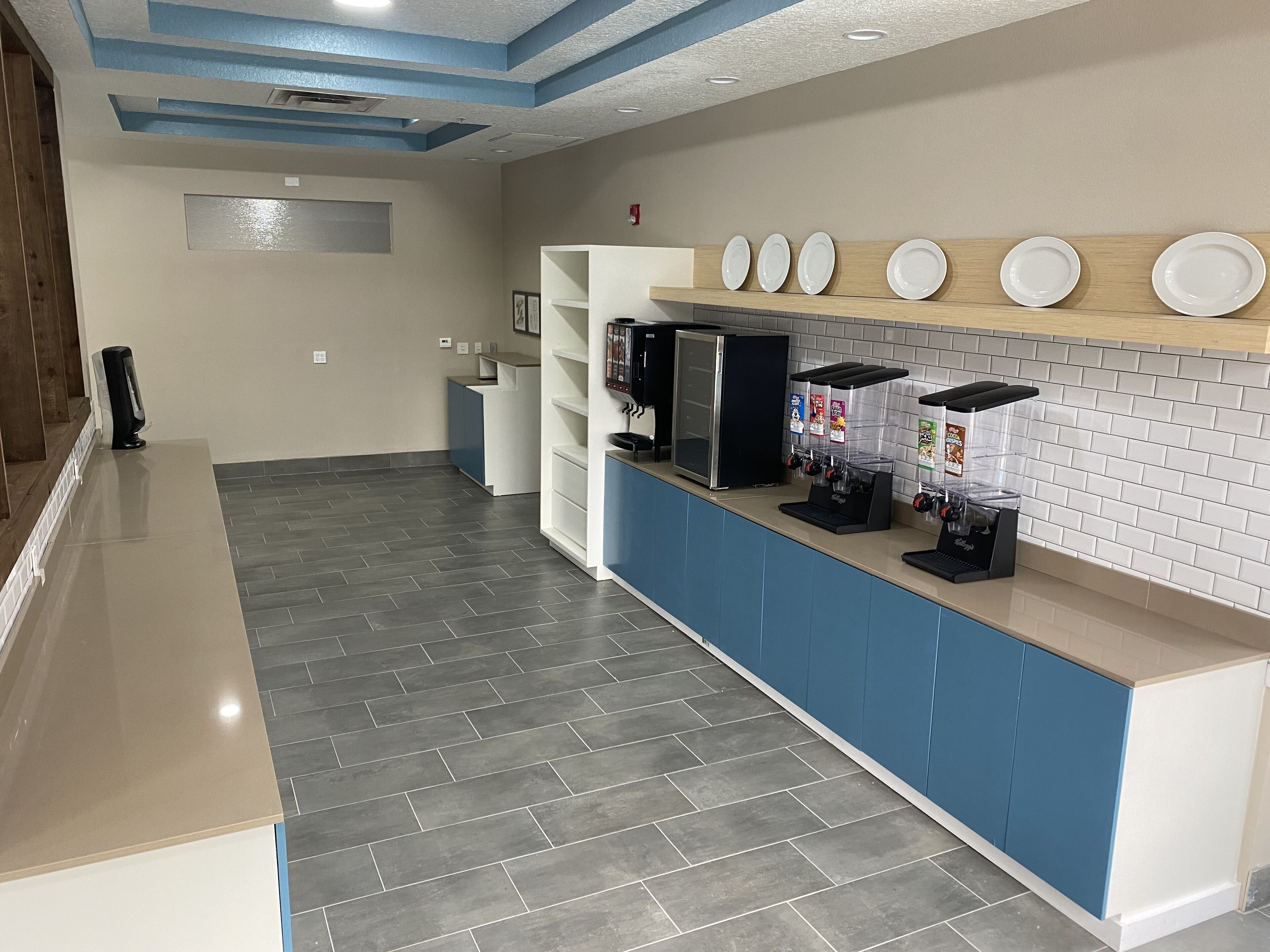 Una zona de recepción limpia y moderna, con mostrador, máquina de café y refrigerador.